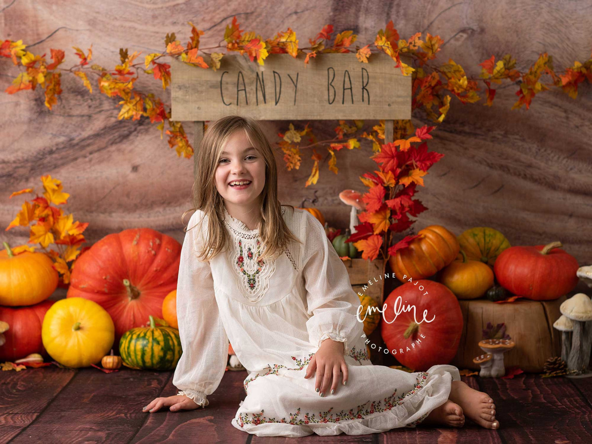 Fond photo d'Halloween Pumpinks – stand de citrouilles devant mur de rondins | Colors&Drops