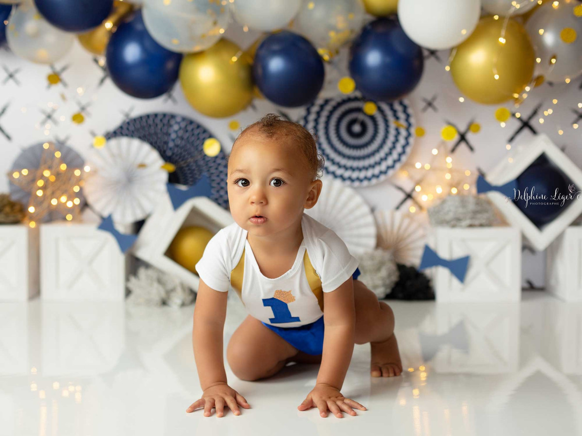 Fond photo bébé et smash cake Fiesta – arche de ballons bleus, dorés et blancs avec rosaces | Colors&Drops