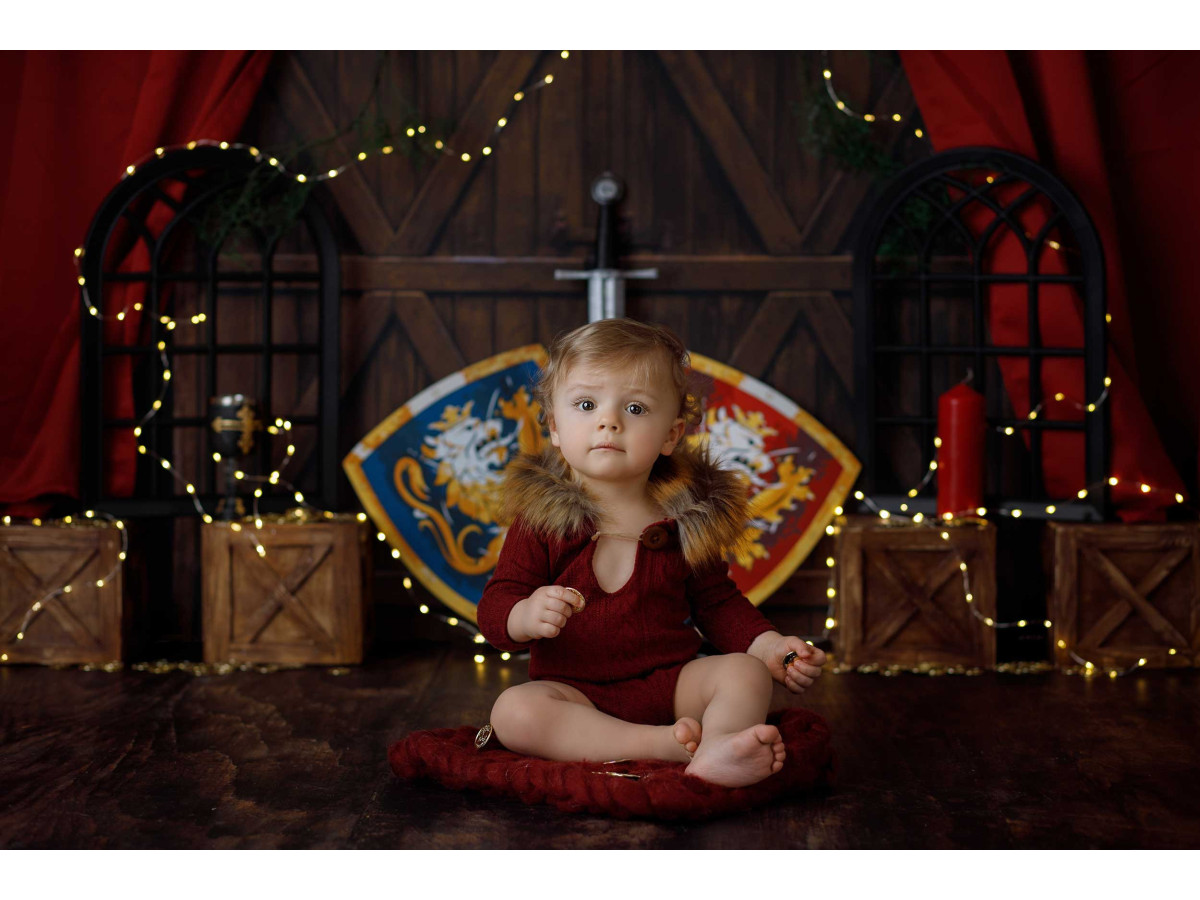 Fond photo bébé et smash cake Chevalier – décor chevalier avec boucliers, épée et rideaux rouges | Colors&Drops