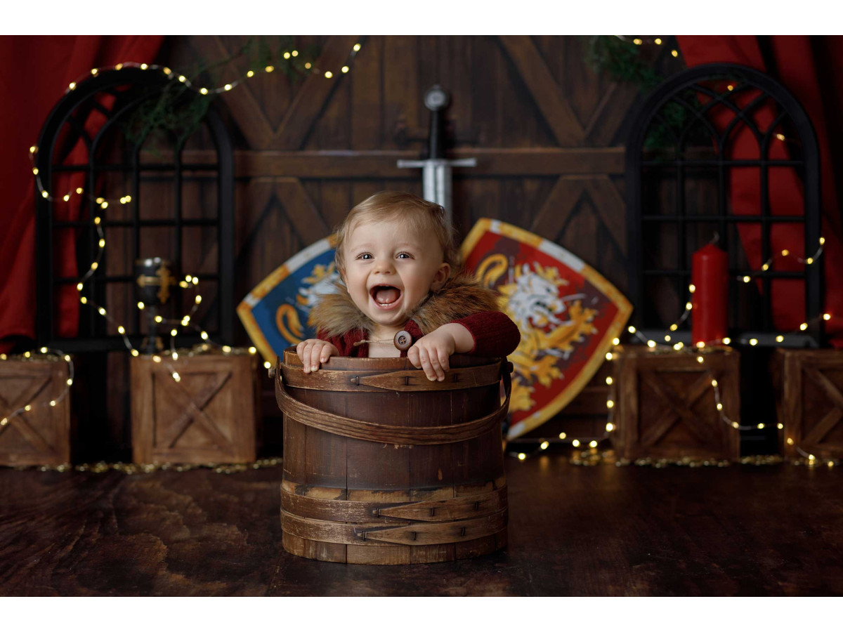 Fond photo bébé et smash cake Chevalier – décor chevalier avec boucliers, épée et rideaux rouges | Colors&Drops
