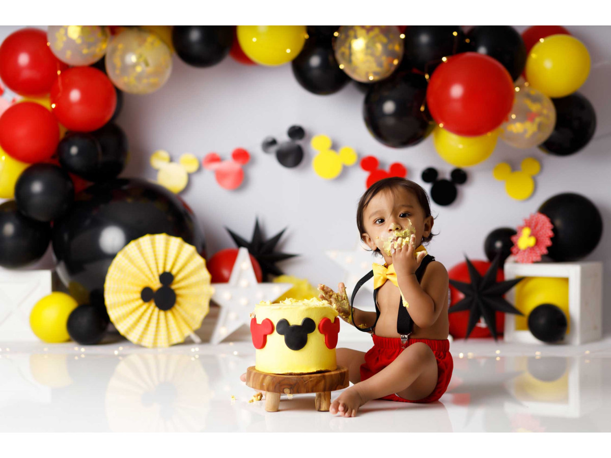 Fond photo bébé et smash cake Micky – arche de ballons rouges, noirs et jaunes avec rosaces | Colors&Drops