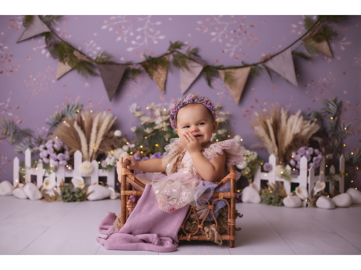 Baby & cake smash photo backdrop Petunia – lilac wall with bunting, flowers and white fence | Colors&Drops