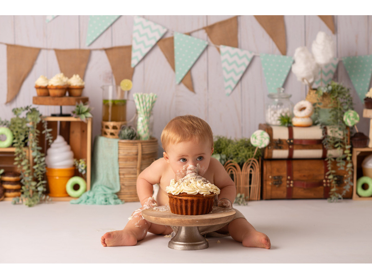 Fondo fotográfico de bebé y smash cake Hum des Donuts – banderines sobre pared de madera con donuts y cajas | Colors&Drops