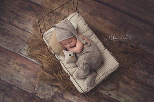 session photo naissance avec bébé allongé sur un lit, sol photo imitation parquet bois vieilli