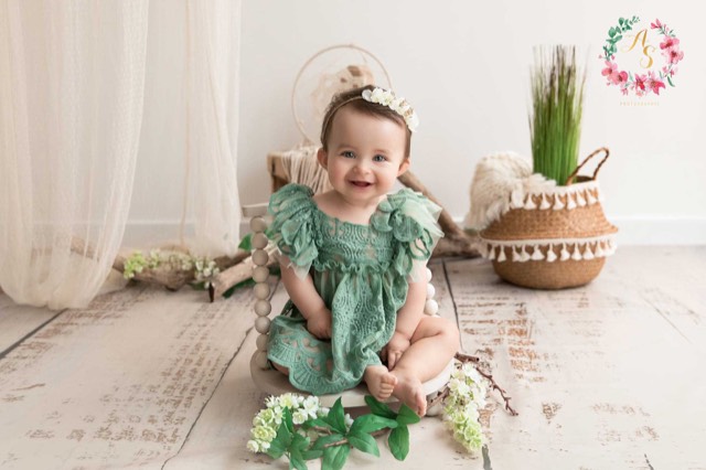 sol en imitation bois beige vieilli, séance photo bébé assis avec robe verte, ambiance bohéme, fond photo