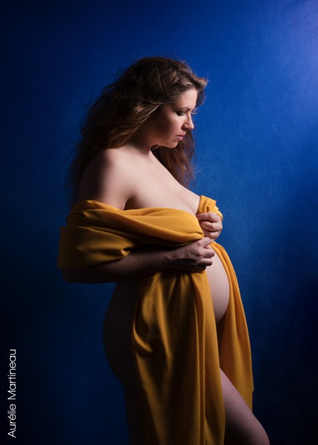 Fond photo uni bleu royal, photo de femme enceinte avec une robe drapée jaune moutarde