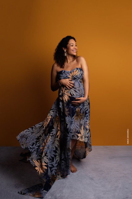 Fond photo jaune orangé, séance photo femme enceinte portant une longue robe fluide à fleurs, Fond photo