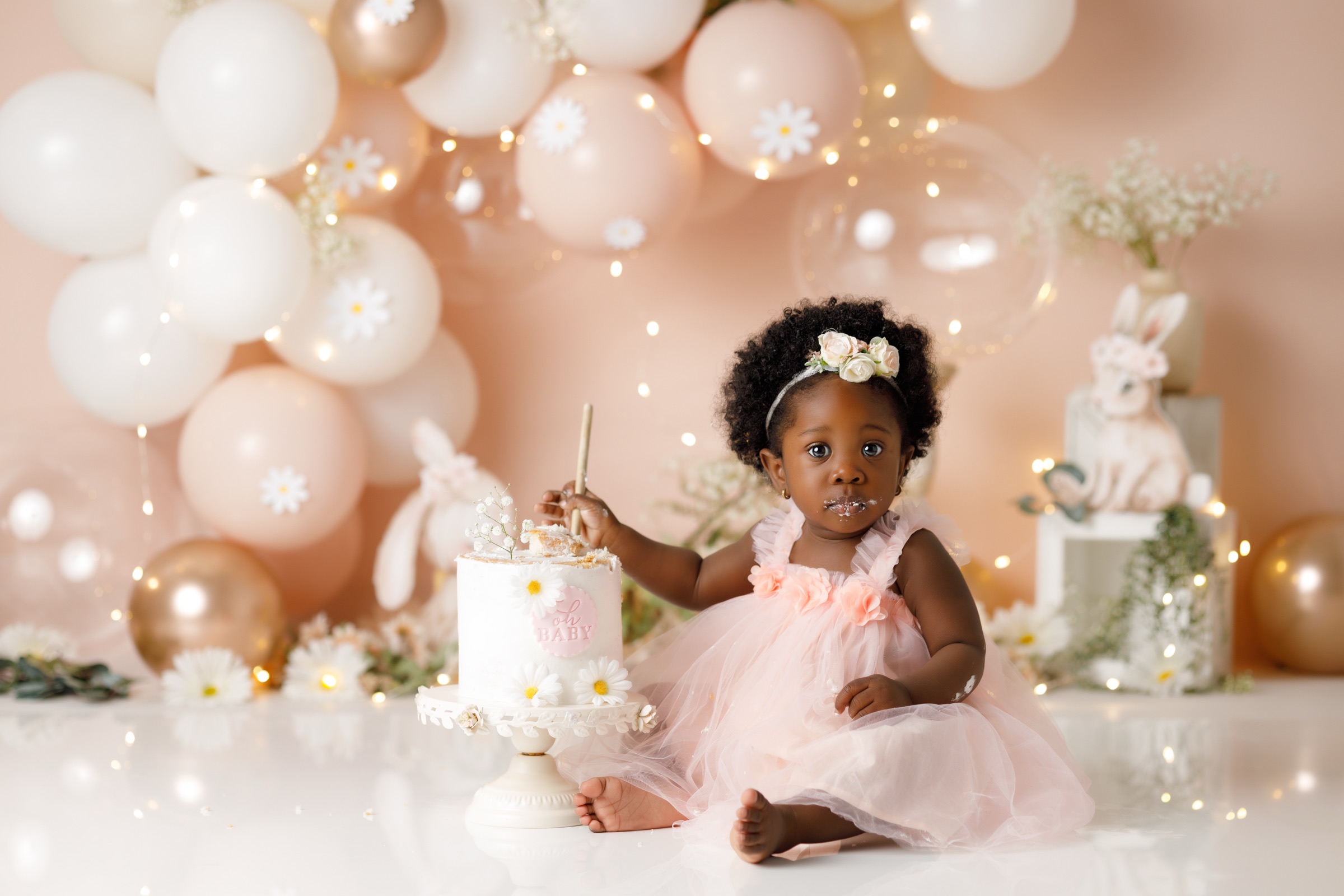 Petite fille en robe rose devant son gâteau, séance smash cake sur un décor Colors & Drops